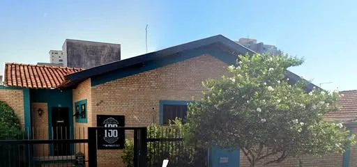 Fachada da Barbearia 198: casa térrea de tijolinho com esquadrias azul-petróleo, placa preta 198 e árvore na frente